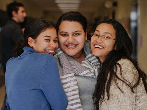 Three student friends smiling for the camera.